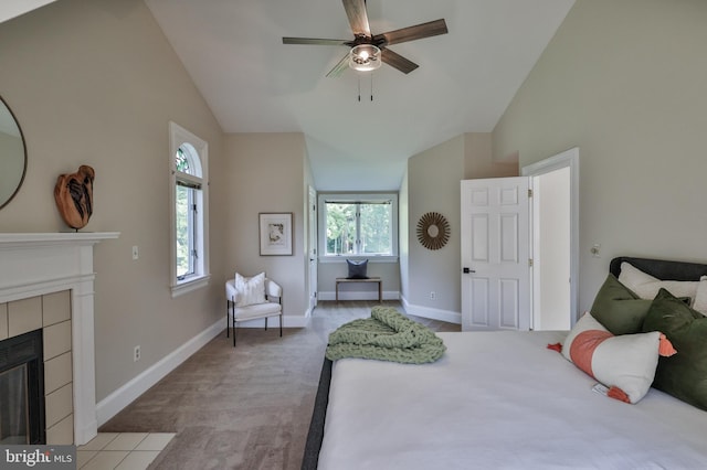 carpeted bedroom featuring ceiling fan, vaulted ceiling, and a tile fireplace