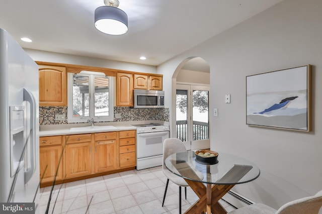 kitchen with baseboard heating, sink, tasteful backsplash, and white appliances