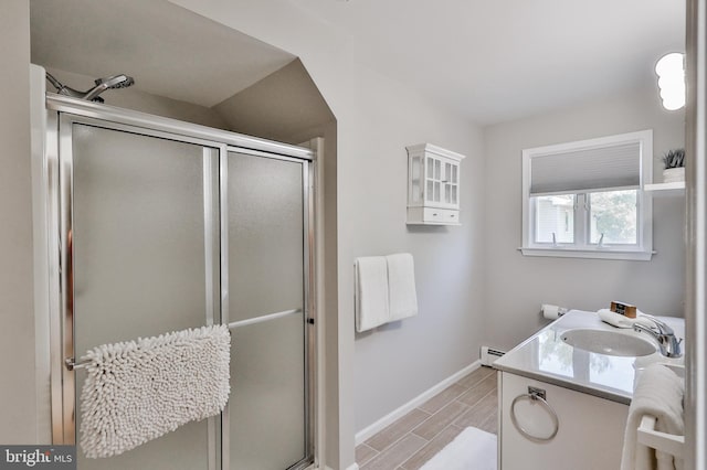 bathroom with a shower with shower door, a baseboard heating unit, and vanity