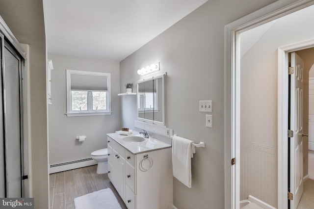 bathroom with toilet, vanity, and a baseboard heating unit