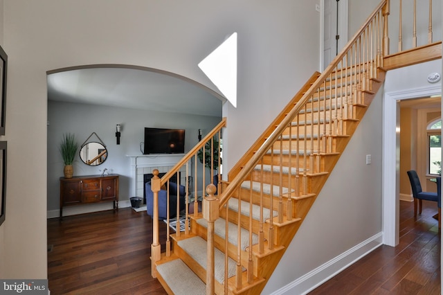 stairway with a tiled fireplace and hardwood / wood-style floors