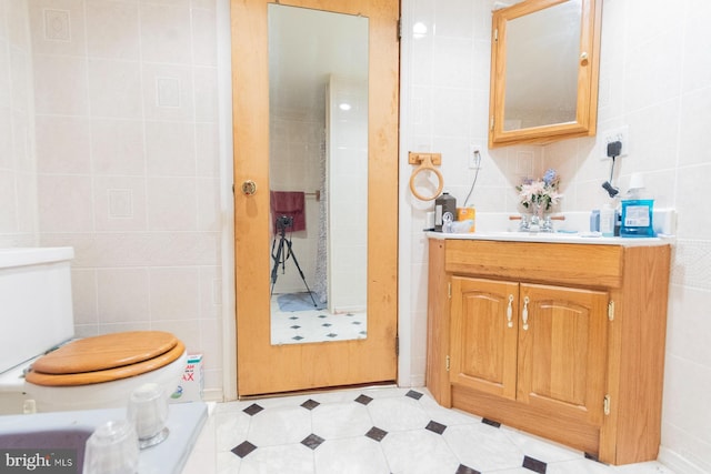 bathroom featuring tile walls, vanity, toilet, and walk in shower