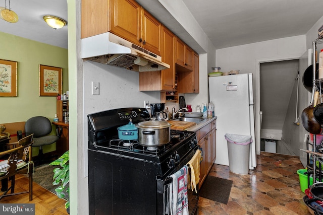 kitchen with sink, black gas range oven, and white refrigerator