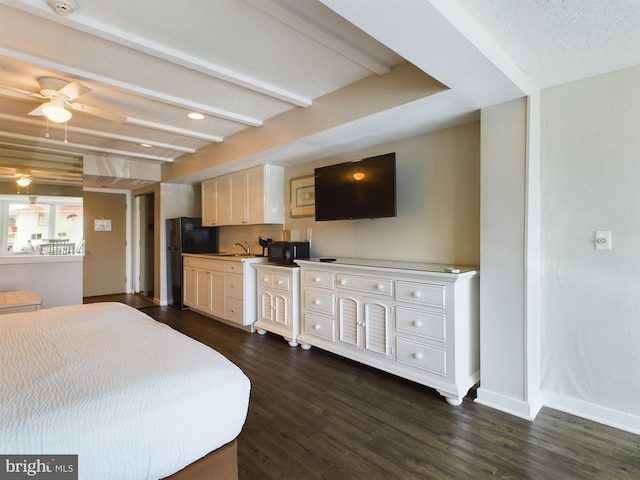 bedroom with sink, black refrigerator, dark hardwood / wood-style floors, ceiling fan, and beam ceiling