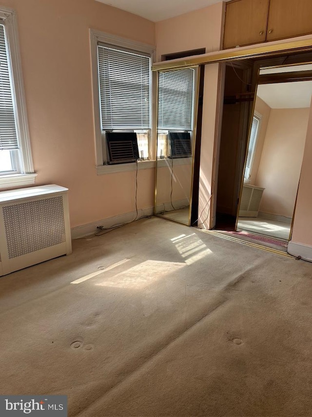 unfurnished bedroom with radiator, cooling unit, and light carpet