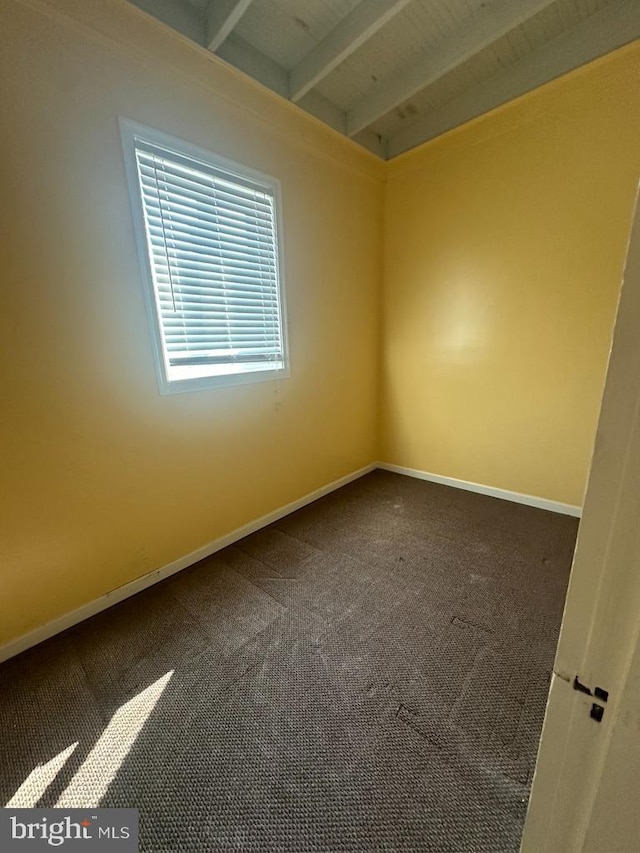 carpeted spare room with beam ceiling