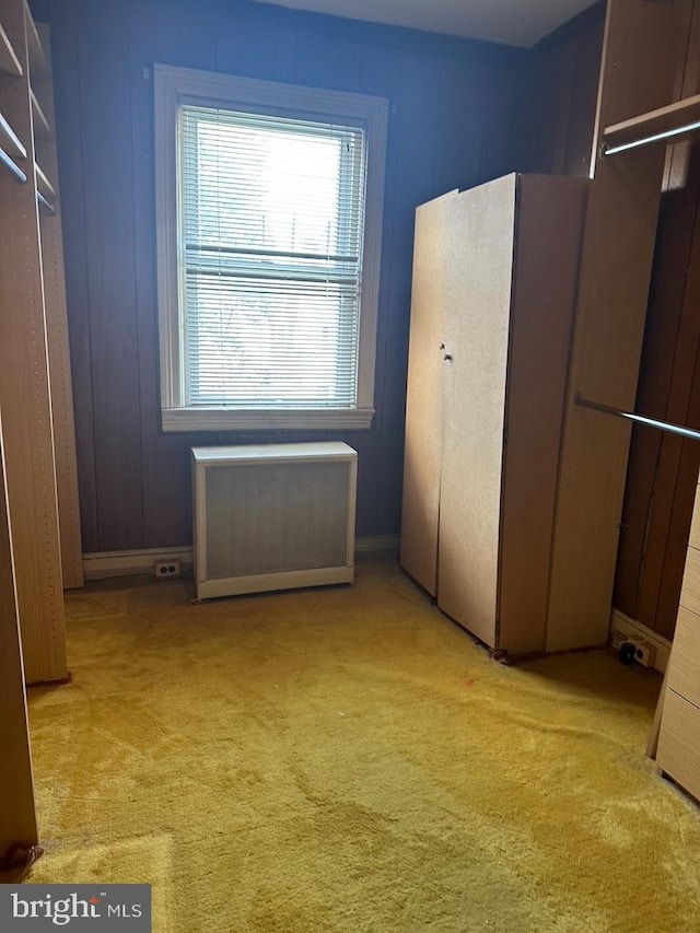 unfurnished bedroom with light colored carpet and radiator