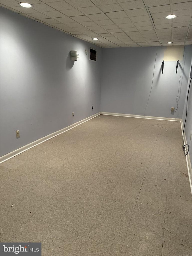 tiled spare room featuring a paneled ceiling