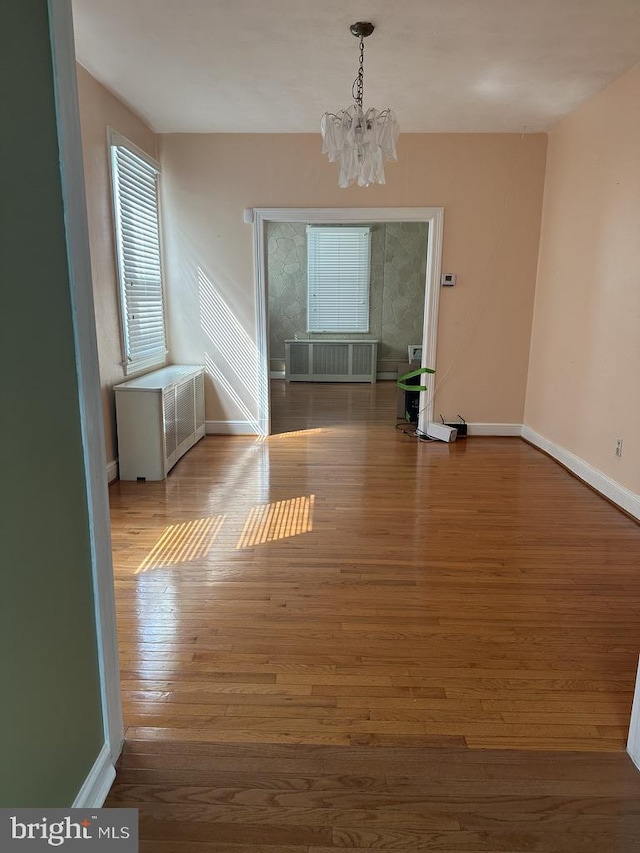 unfurnished room with an inviting chandelier and hardwood / wood-style flooring