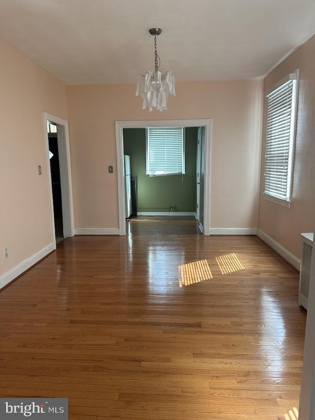 unfurnished dining area with an inviting chandelier and wood-type flooring