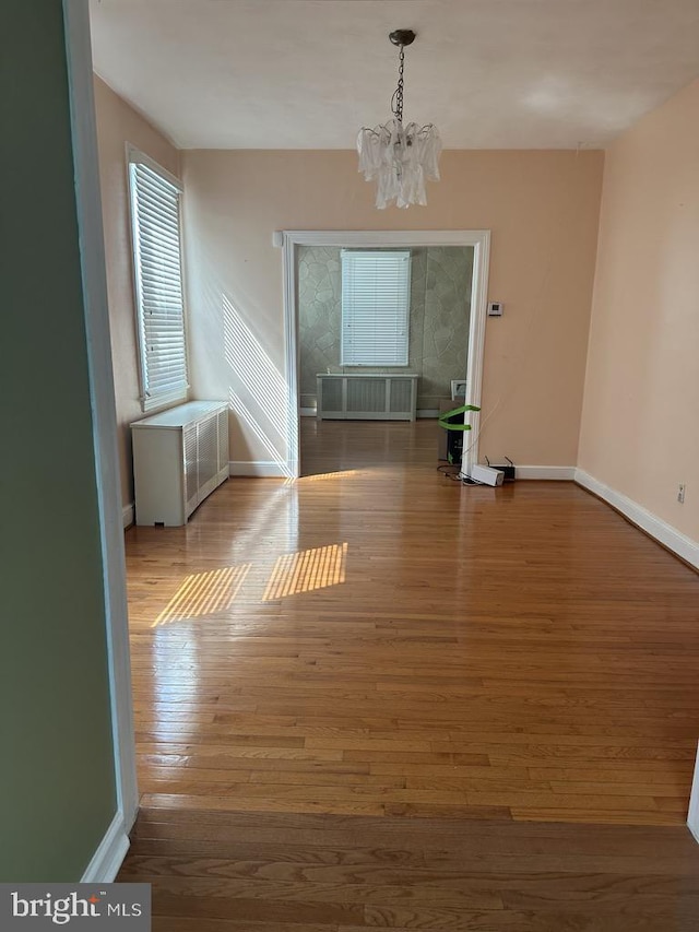 unfurnished room with hardwood / wood-style floors and an inviting chandelier