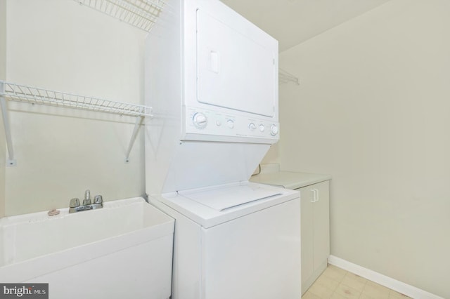 laundry room with sink, light tile patterned flooring, and stacked washer and dryer