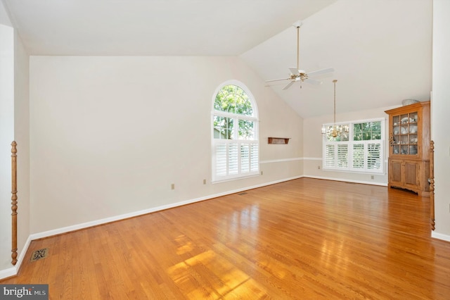 unfurnished living room with lofted ceiling, ceiling fan with notable chandelier, and light wood-type flooring