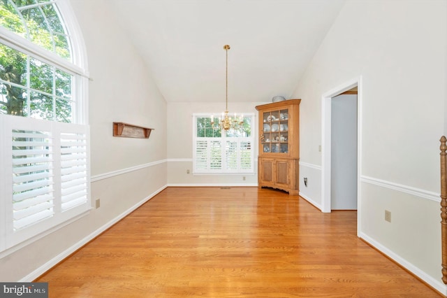 unfurnished dining area with light hardwood / wood-style flooring, vaulted ceiling, and an inviting chandelier