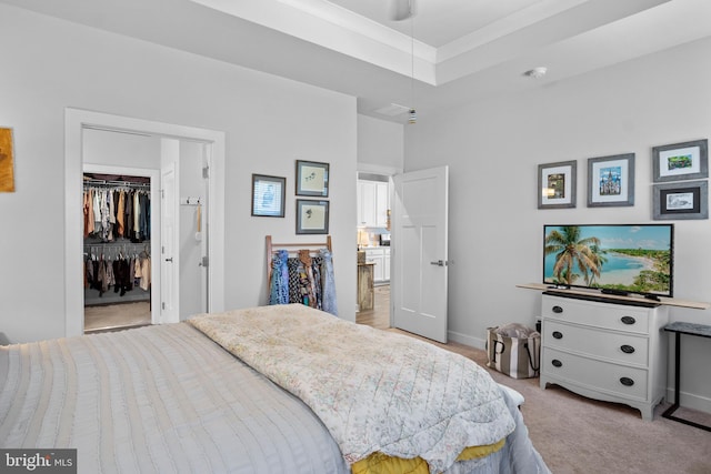 bedroom with a spacious closet, light carpet, a closet, a raised ceiling, and crown molding