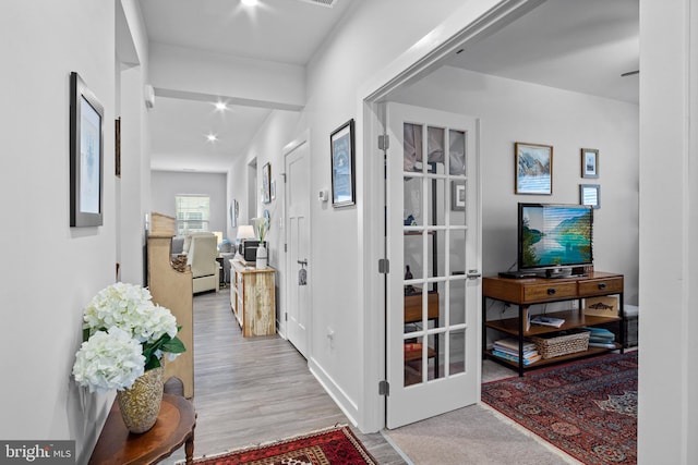 corridor with french doors and light hardwood / wood-style flooring