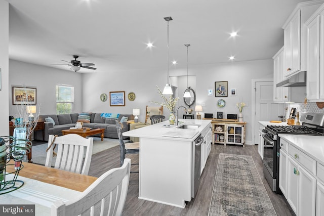 kitchen featuring hanging light fixtures, white cabinets, stainless steel appliances, and a center island with sink