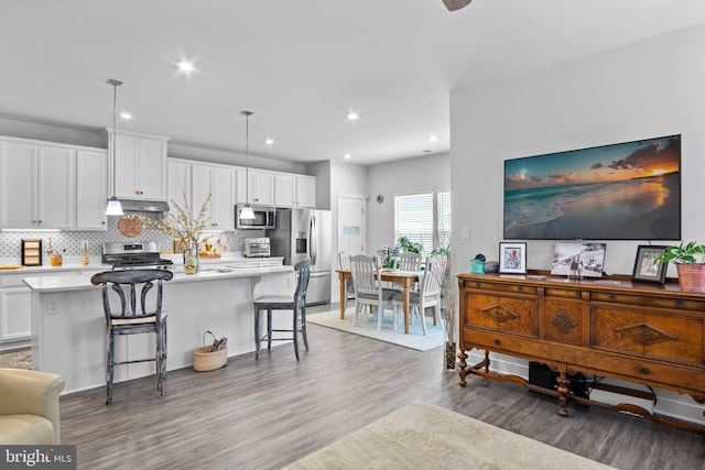 kitchen featuring white cabinetry, appliances with stainless steel finishes, a kitchen breakfast bar, a kitchen island, and pendant lighting