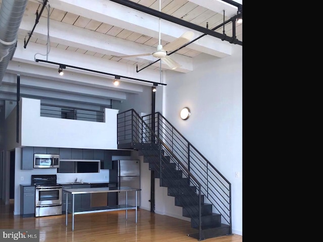 stairway featuring ceiling fan, wood-type flooring, wood ceiling, and beamed ceiling