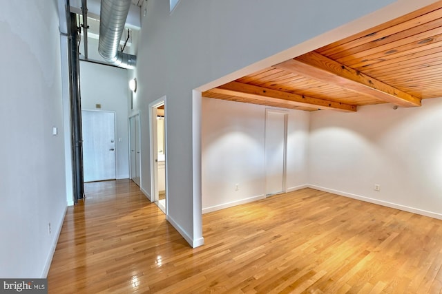 additional living space with a towering ceiling, beamed ceiling, wood ceiling, and light wood-type flooring