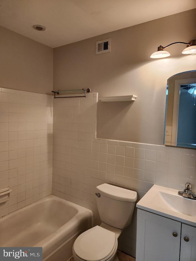 bathroom with toilet, a bathing tub, tile walls, and vanity