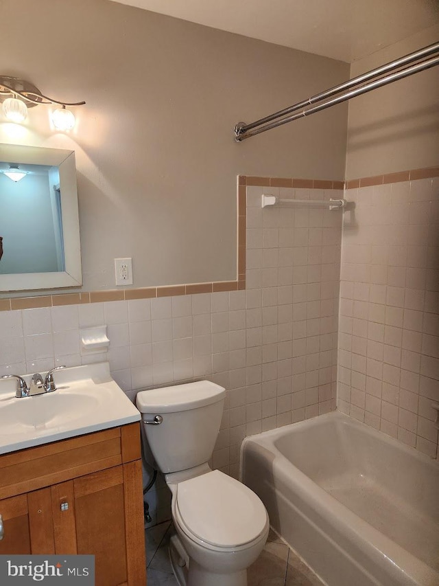 full bathroom with tile walls, toilet, vanity, and tiled shower / bath combo