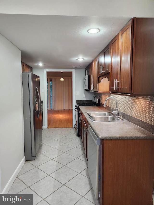 kitchen with light tile patterned floors, sink, appliances with stainless steel finishes, and tasteful backsplash