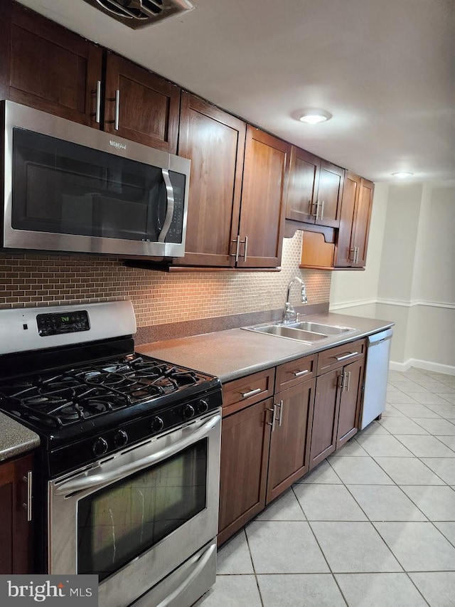 kitchen with light tile patterned floors, backsplash, sink, and stainless steel appliances