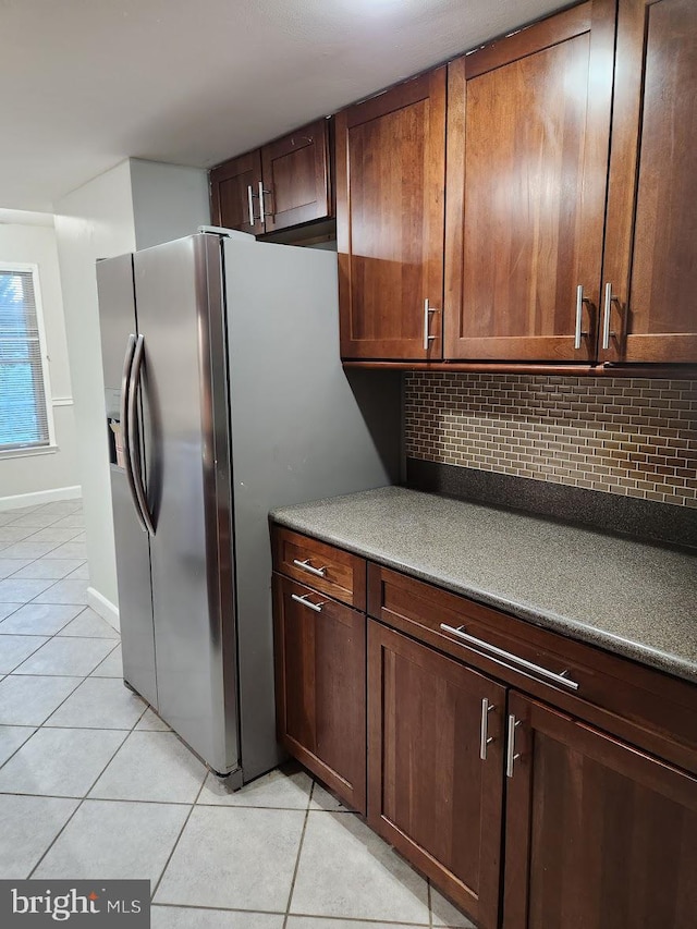 kitchen featuring light tile patterned floors, backsplash, and stainless steel fridge with ice dispenser