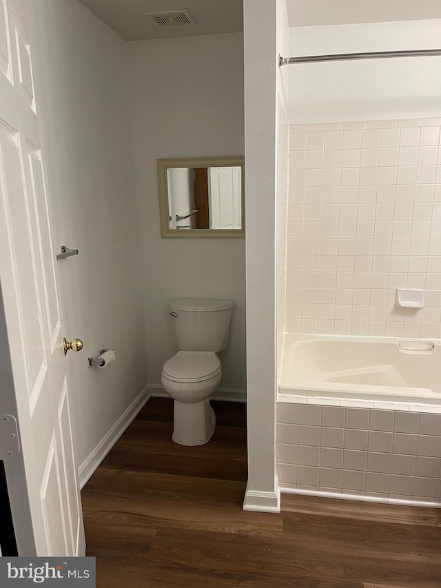 bathroom with toilet, tiled shower / bath combo, and wood-type flooring