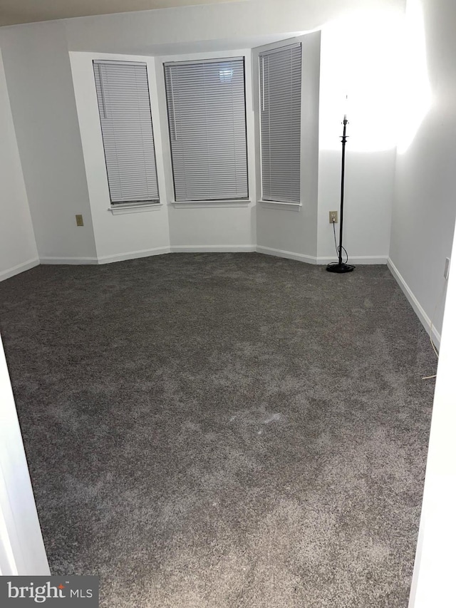 unfurnished room featuring dark colored carpet