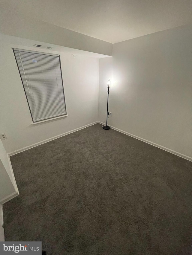 spare room with dark carpet