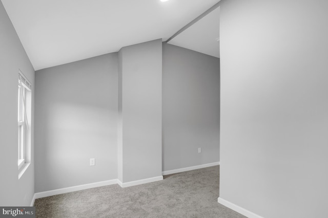 spare room with light colored carpet and vaulted ceiling