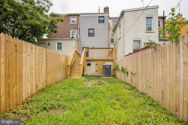 back of property with central air condition unit and a yard