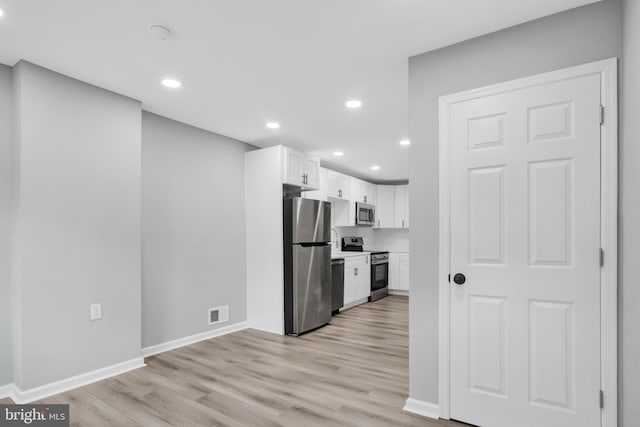 kitchen with white cabinets, light wood-type flooring, and appliances with stainless steel finishes