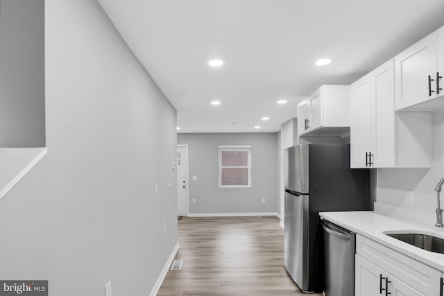 kitchen featuring light stone countertops, dishwasher, white cabinets, and sink