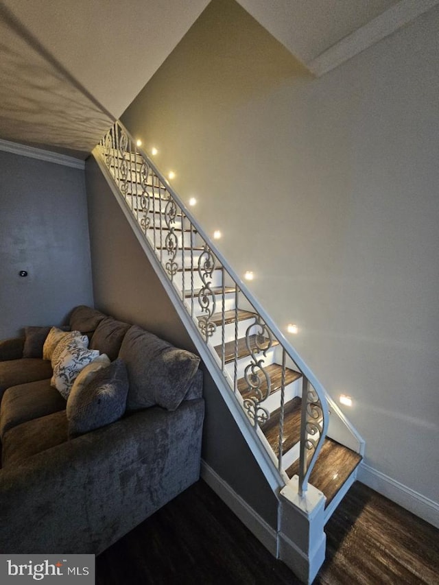 stairs with crown molding and dark wood-type flooring