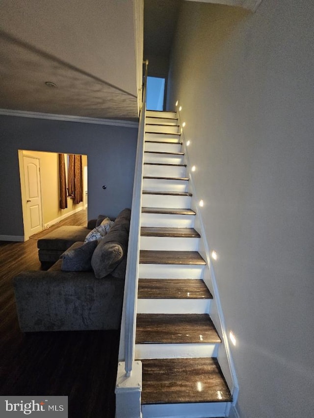 stairway with wood-type flooring and ornamental molding