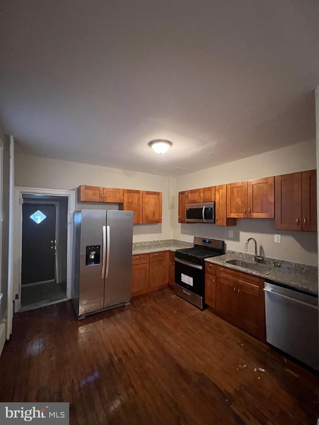 kitchen with appliances with stainless steel finishes, sink, and dark hardwood / wood-style floors