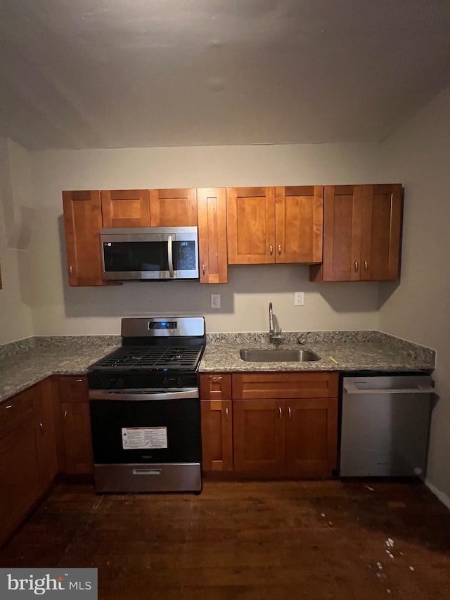 kitchen featuring dark hardwood / wood-style floors, stainless steel appliances, light stone counters, and sink