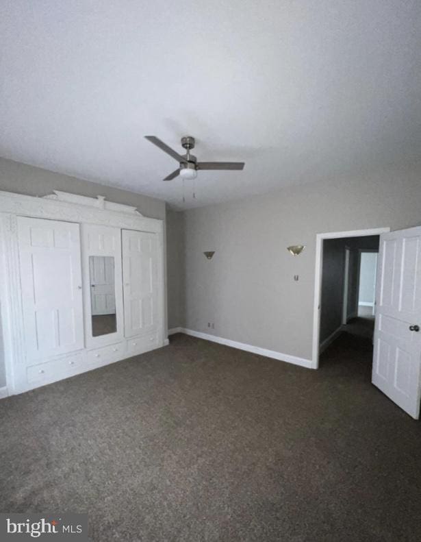 unfurnished bedroom with ceiling fan and dark carpet