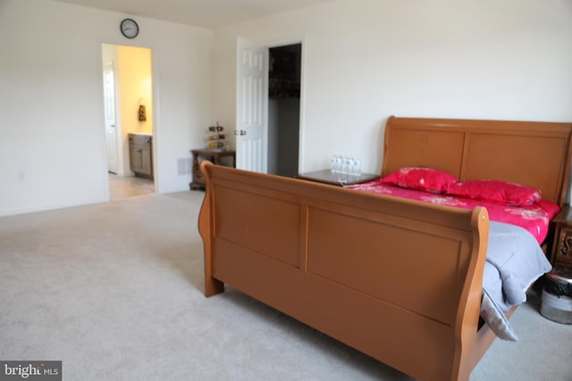 bedroom with light colored carpet and ensuite bathroom