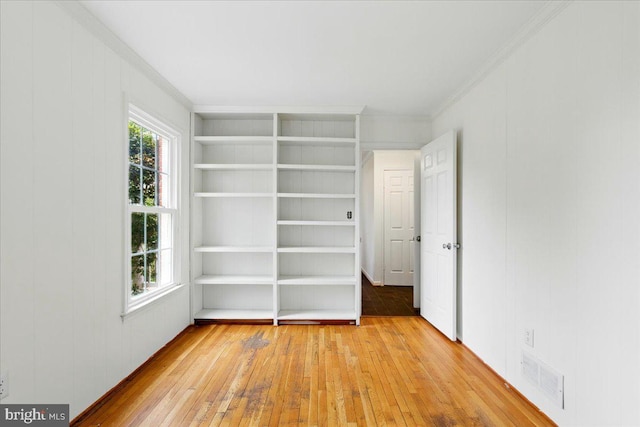 spare room with ornamental molding, visible vents, and light wood finished floors