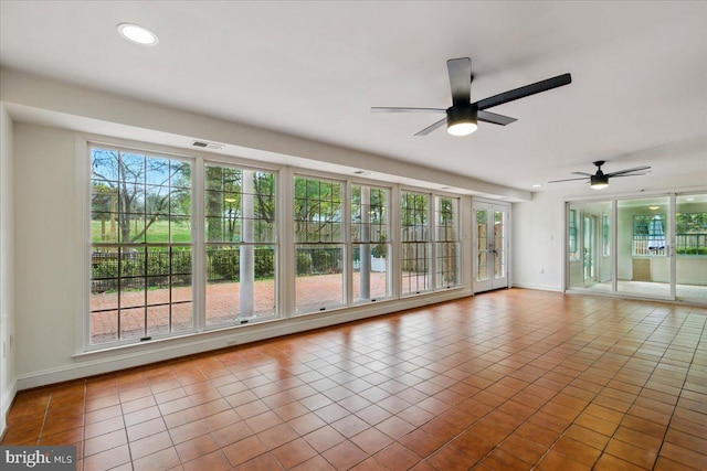 empty room featuring baseboards, a wealth of natural light, and ceiling fan
