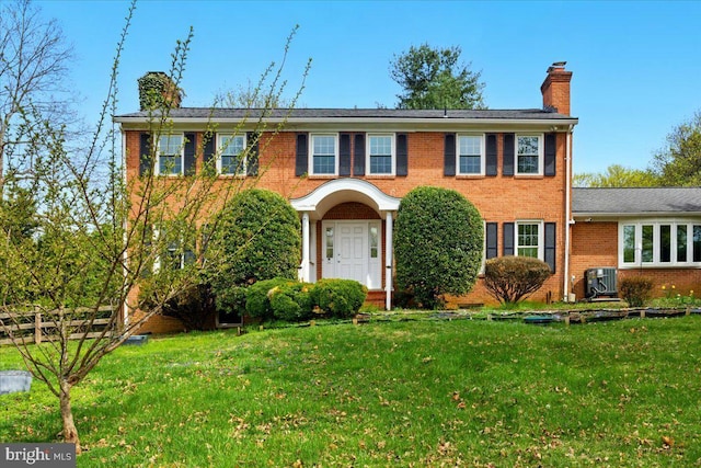 colonial house featuring a front lawn, a chimney, and brick siding