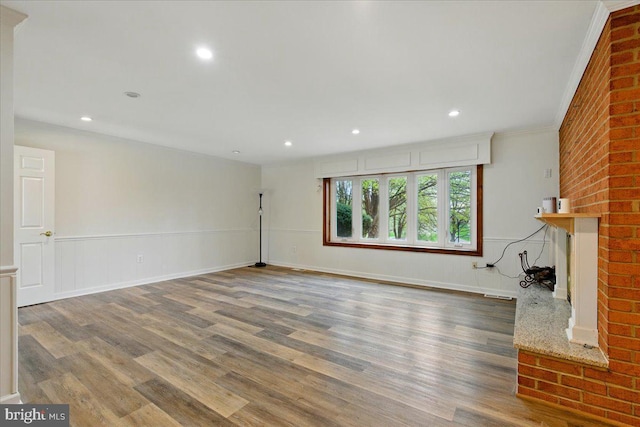 unfurnished living room featuring a brick fireplace, wood finished floors, and recessed lighting
