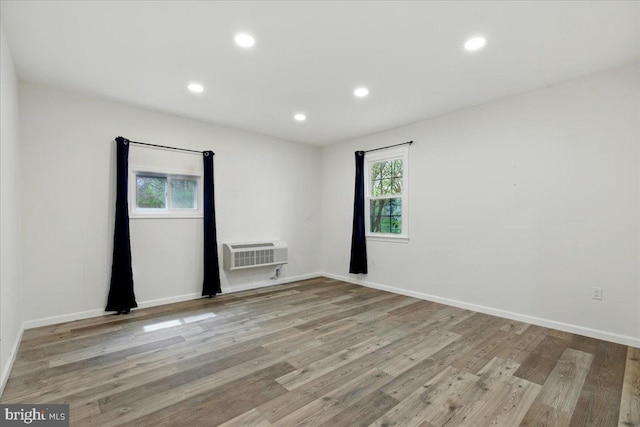 empty room with wood finished floors, a healthy amount of sunlight, recessed lighting, and a wall mounted air conditioner