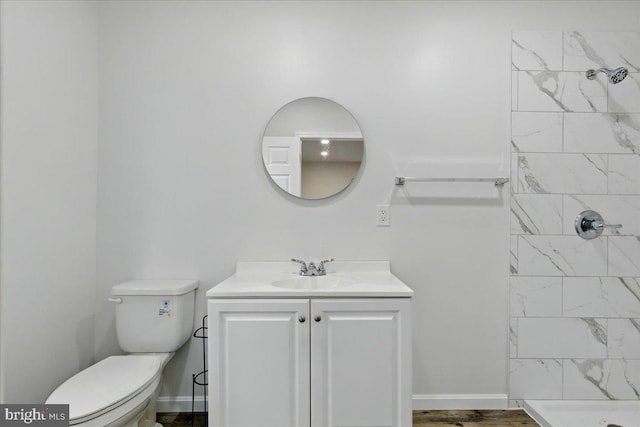 bathroom featuring toilet, vanity, and tiled shower