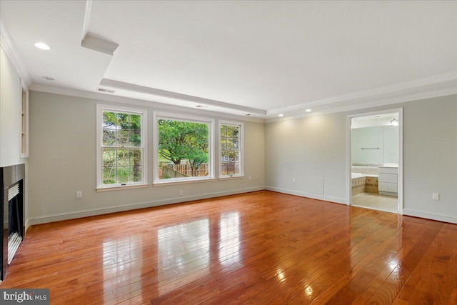 unfurnished living room with plenty of natural light, a tray ceiling, and ornamental molding