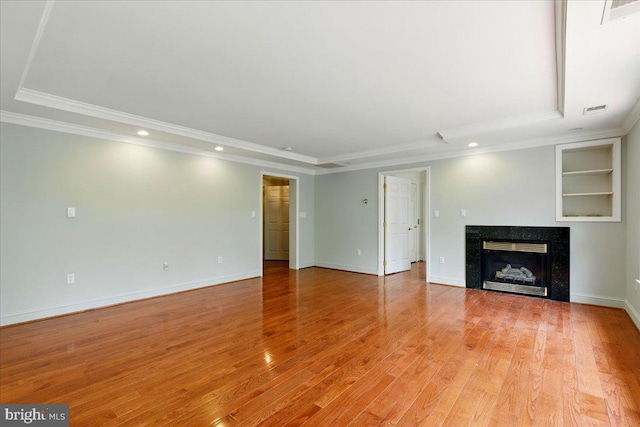 unfurnished living room with crown molding, light wood-type flooring, and a raised ceiling